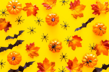 Halloween pattern with pumpkins, spiders and bats on yellow background top view