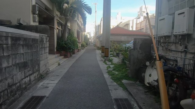 POV Walking down a residential street alley past houses and apartment buildings. Ishigaki, Okinawa, Japan. Circa September 2019