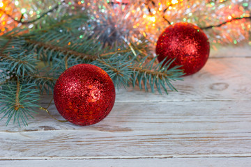 Greeting card. Red christmas balls on wooden background, spruce branch, bokeh.