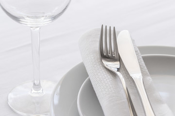 Close up of silverware fork and knife with napkin on white porcelaine plate. Copy space. Restaurant dinning concept.