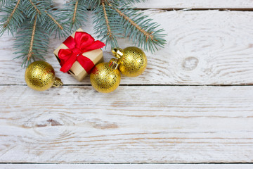 Flatlay greeting card with space for your text. Fluffy fir branch, golden balls to decorate the Christmas tree and two New Year's gifts from Santa Claus on a light wooden table.