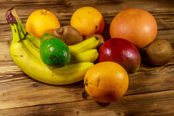 Assortment of tropical fruits on wooden table. Still life with bananas, mango, oranges, avocado, grapefruit and kiwi fruits
