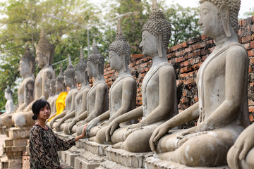 An asian girl exploring the rows of Buddha statues in Wat Yai Chai Mongkon in Ayutthaya Historical Park
