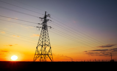 Fototapeta premium Silhouette High voltage electric towers at sunset time. High-voltage power lines. Electricity distribution station
