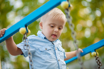 A boy with Down syndrome plays in the playground. Genetic disease in a child.