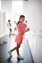 Fototapeta na wymiar Curly girl wearing pink clothing standing near locker