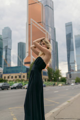 Outdoor portrait of beautiful young woman with skyscrapers on the background.