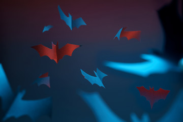 Photo of blue and red flying paper bats on empty halloween background.