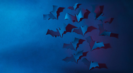 Halloween image of blue paper bats flying up on dark blue background.