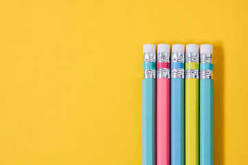 top view group of wooden pastel color pencils on yellow paper background with copy space, flat lay