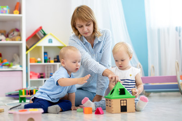 Nursery babies and kindergarten teacher playing with educational toys