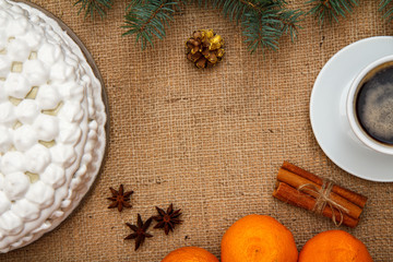 Biscuit cake decorated with whipped cream, cup of coffee, oranges, star anise and cinnamon