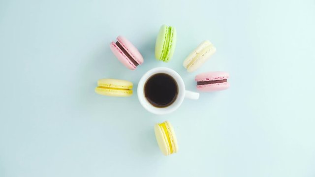 Macaroons or macaron on pastel blue surface with espresso in white cup.