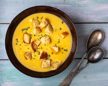 Homemade soup-mashed vegetables in mushroom broth with croutons in a deep dish and tablespoons
