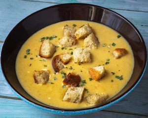 a plate of mashed soup with fried croutons on a wooden tray