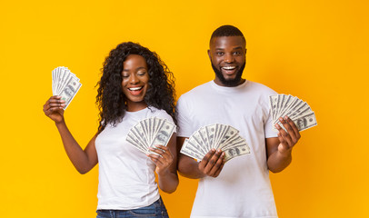 Cheerful black couple holding money and smiling