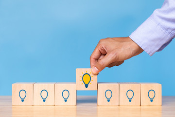 Hand hold wooden cube with choose bright light bulb. Concept of Idea, solution and creative