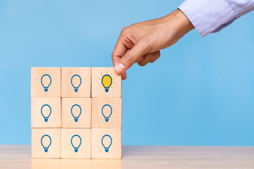 Hand hold wooden cube with choose bright light bulb. Concept of Idea, solution and creative