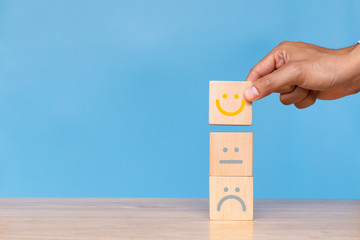 Hand of client show a feedback with smiley face wood cube. Service rating, satisfaction concept