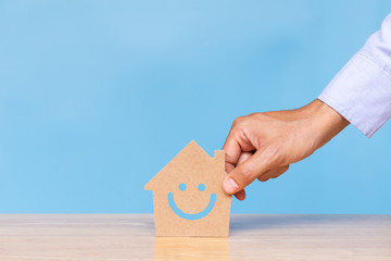 House model and wooden cubes with smiley face icon on blue background