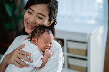 asian mother embrace carrying newborn little daughter with love