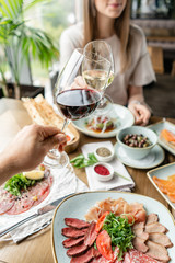Portrait of a beautiful young elegant woman in the restaurant with a wine glass. Dinner and a variety of dishes on the table. Italian cuisine