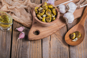 Grilled olives with garlic, olive oil and spices on rustic wooden table