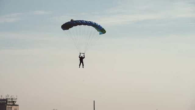 Parachuter landing with a square parachute in a large field in autumn in slo-mo  