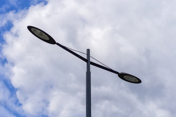 Modern street lamp against the sky with clouds.