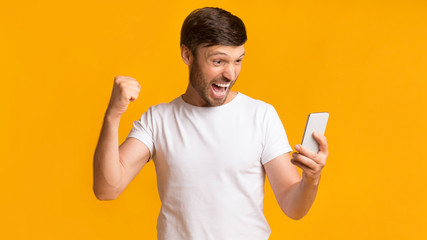 Happy Man Holding Cellphone Shaking Fists Celebrating Success, Panorama