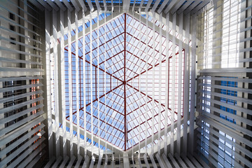 Looking up at the skylight glass roof of an atrium, with geometric structure in modern contemporary...