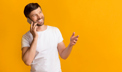 Happy Man Talking On Phone Standing On Yellow Background