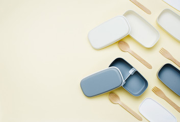 Open empty lunch boxes and wooden forks and spoons on yellow background