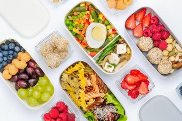 Pattern of plastic lunch boxes filled with healthy food, fresh fruits and berries on white...
