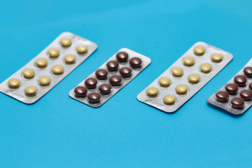 Set of pills blisters isolated on solid blue background. Medical concept. Potent drugs. Brown pills.