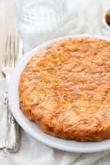 Traditional spanish food Tortilla with potato on white dish and olives in small bowl on ceramic background.
