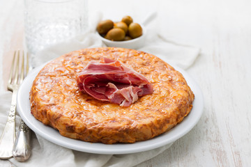 typical spanish food Tortilla with smoked meat and potato on white dish