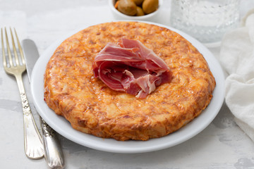 typical spanish food Tortilla with smoked meat and potato on white dish