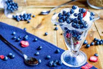 Tasty and healthy breakfast with muesli, yogurt and blueberries on a wooden table.