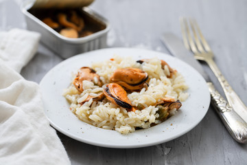 rice with mussels on small white plate on ceramic background