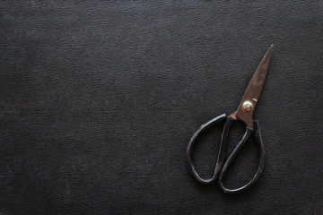 Black leather texture background with old vintage Scissors