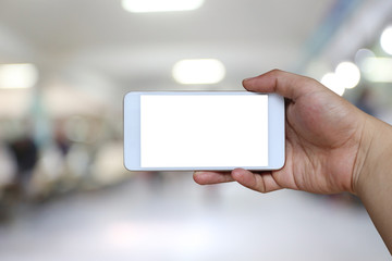 Hand of a man holding smartphone device on blur hospital background.