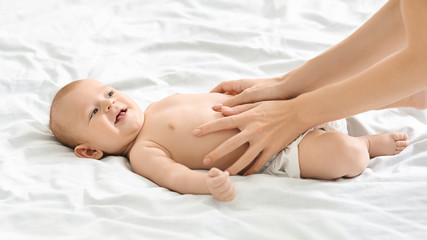 Fototapeta na wymiar Mother massaging tummy of newborn baby to prevent colics
