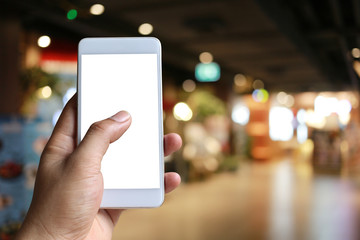 Hand of a man holding smartphone device in the Shopping mall background.