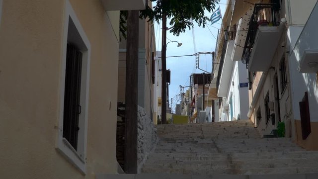 Static view of uphill road in Syros with greek flag waving from building