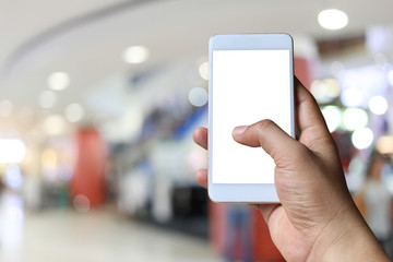 Hand of a man holding smartphone device in the blur Shopping mall background.