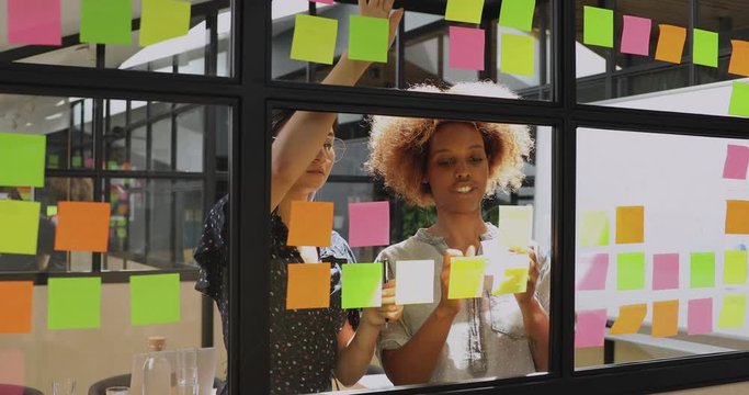 Two african and asian businesswomen working with sticky notes