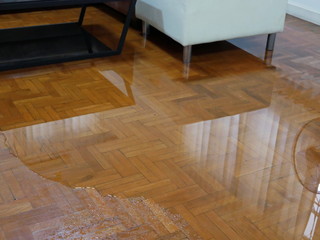 Water spreading / flooding on living room parquet floor in a house - damage caused by water leakage