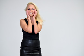 Concept portrait of a pretty young blonde woman with long beautiful hair in a black suit on a white background in studio. Standing in front of the camera in various poses with a smile.