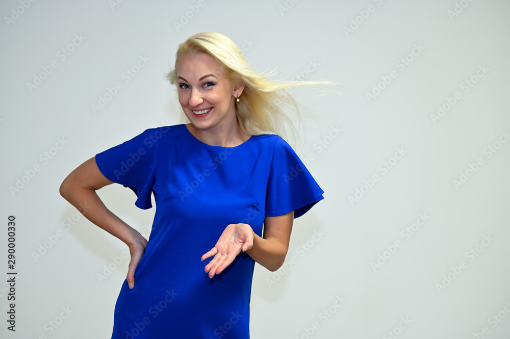 Wall mural concept portrait of a pretty young blonde woman with long beautiful hair in a blue dress on a white 